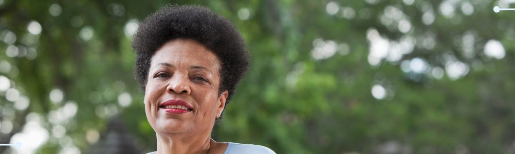A woman in the park smiling towards the camera.